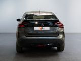 the rear end of a grey car in a white room
