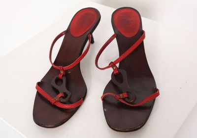 paire de sandales brunes et rouges avec des lanières rouges sur une surface blanche
