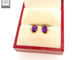 pair of purple stone stud earrings in a red box on a white surface