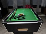 une table de billard recouverte d'un tapis vert, dans une pièce