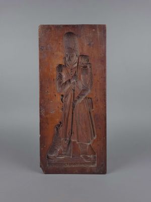 une plaque en bois sculptée représentant un homme tenant un bâton