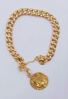 un bracelet en or orné d'un pendentif en forme de pièce de monnaie