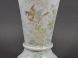 a white vase with a bird on it on a table