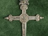 une croix en argent sur un fond de velours vert orné d'un motif décoratif
