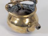 a gold pot with a handle on a white surface