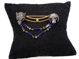 a close up of a black pillow with a gold and blue broochle
