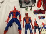 spider - man action figures and other toys are on a bed