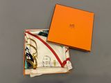 une boîte orange avec un foulard blanc et une boîte jaune sur laquelle figure le portrait d'une femme