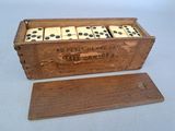 une vieille boîte en bois posée sur une table, contenant quatre dominos