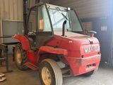 un tracteur rouge garé à l'intérieur d'un bâtiment, dans un garage