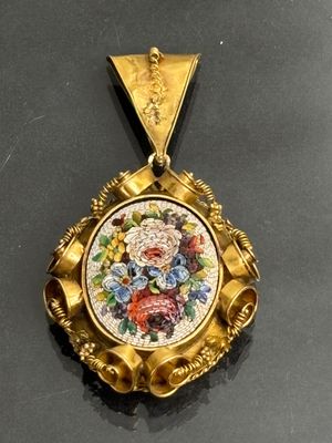 a gold pendant with a picture of flowers on it