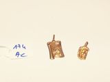 two small gold charms are sitting on a white surface next to a piece of paper