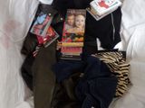 a pile of clothing and books on a bed