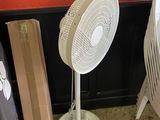 a white fan sitting next to a stack of boxes