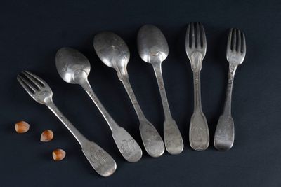 six forks and spoons with nuts on a black surface