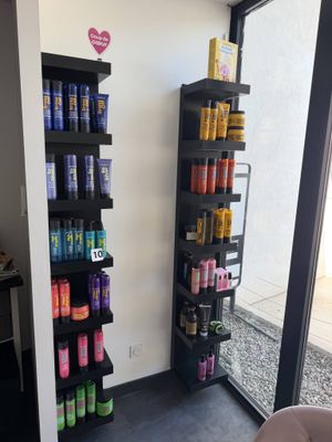 des rayons de produits capillaires dans un salon de coiffure, avec vue sur l'extérieur