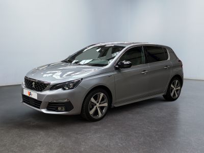 La voiture argentée est garée dans une pièce blanche au sol noir