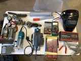 a table with many tools on it that include a welding mask, wire cutters, and other tools