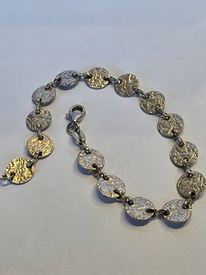 un gros plan d'un bracelet en argent et en or posé sur une surface blanche