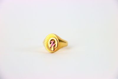 un gros plan d'une bague en or ornée d'un ruban rose