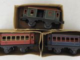 trois petits trains miniatures posés dans une boîte sur une surface blanche