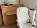 une chaise de bureau blanche placée devant un bureau et un radiateur