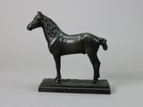 statue en bronze représentant un cheval, posée sur un socle noir, sur fond blanc
