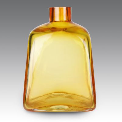 une bouteille en verre jaune avec un bouchon doré, posée sur une surface blanche