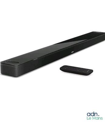 La barre de son est noire et est accompagnée d'une télécommande posée à côté.