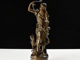 une statue en bronze d'une femme tenant un oiseau sur un piédestal