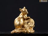 une figurine en or représentant une souris tenant une pièce d'or