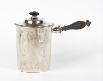 une vieille casserole en argent avec une poignée en bois posée sur une surface blanche