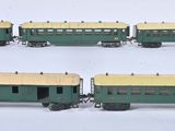 quatre wagons verts et jaunes alignés les uns à côté des autres sur une surface blanche