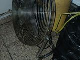 un ventilateur posé par terre à côté d'un sac poubelle