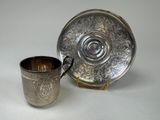 a silver cup and saucer sitting next to each other