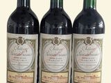 trois bouteilles de vin rouge posées l'une à côté de l'autre sur une surface blanche