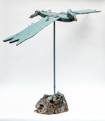 une photo d'une sculpture métallique représentant un oiseau posé sur un rocher