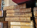 several old books stacked on top of each other on a shelf