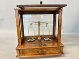 an old wooden balance scale with a glass case on top of it