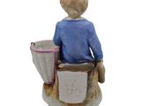 a figurine of a boy sitting on a chair with a basket
