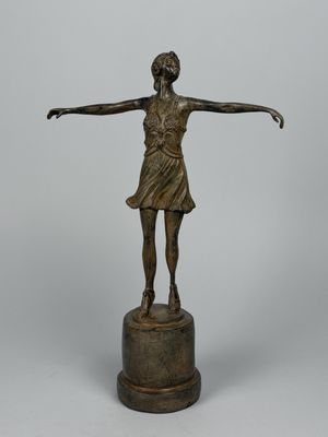 statue en bronze représentant une femme debout sur un socle, les bras tendus