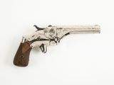 un vieux pistolet avec une poignée en bois sur une surface blanche