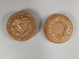 two gold coins sitting on top of each other on a white surface