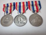 three medals are shown on a white surface with red, white, and blue ribbons