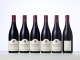 six bottles of red wine lined up on a table