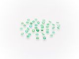 a pile of green glass beads on a white surface