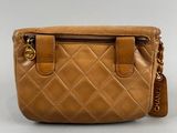 a tan leather purse with a chain strap and zipper closure