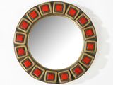 une image représentant un miroir rond orné d'un motif rouge et or