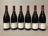 six bouteilles de vin sont alignées sur une table