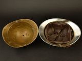 an old helmet and a metal bowl on a black surface